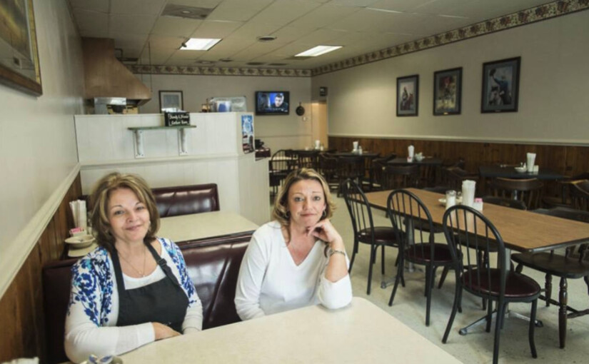 two women sitting at a table in a diner