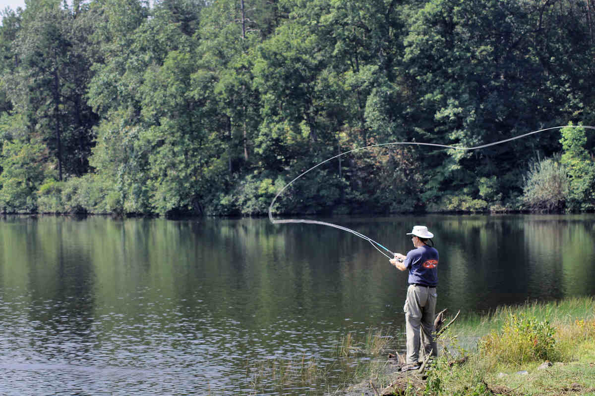 man fishing on side of lake
