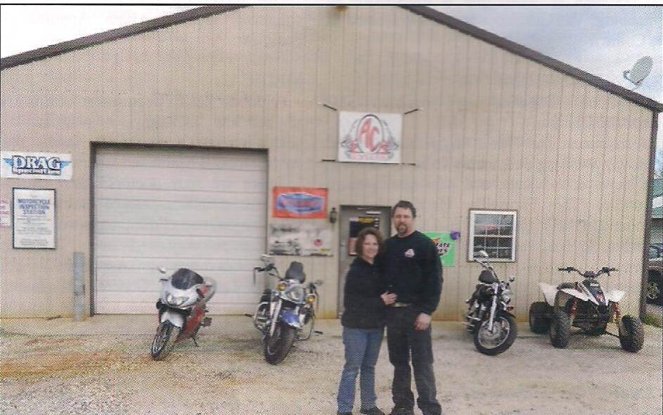 Man and woman standing in front of a shop with motorcycles and ATV