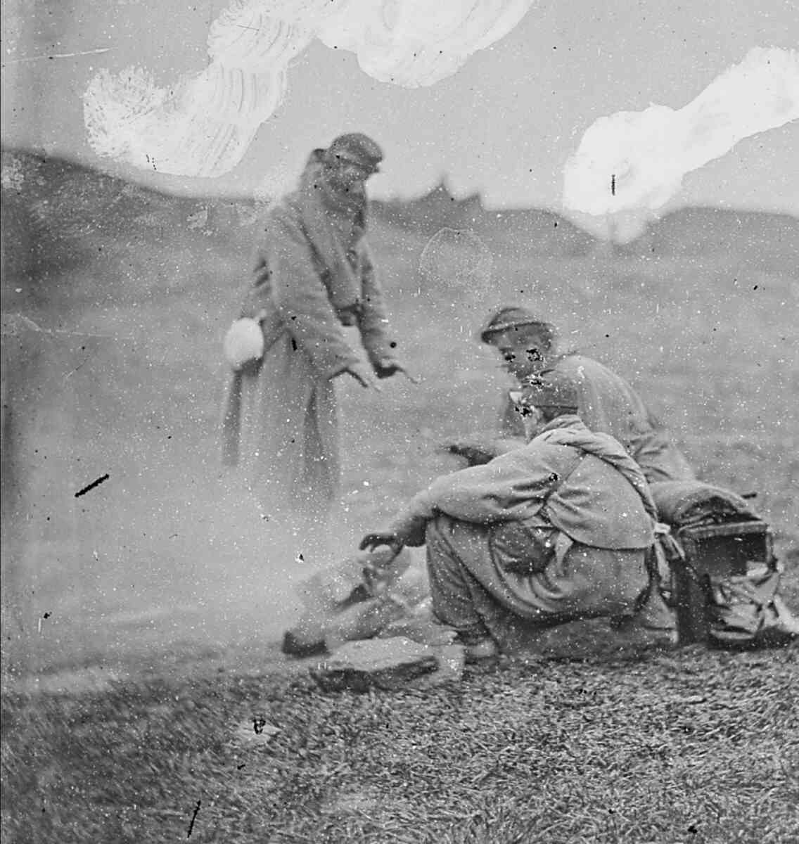 Men sitting around fire on battlefield