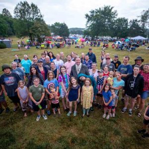 Large group of adults and children gathered in field