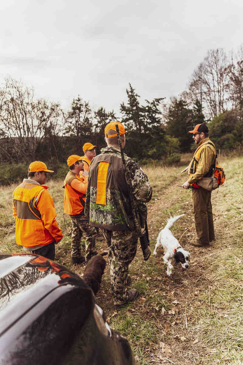 Men in hunting clothing with rifle and dog