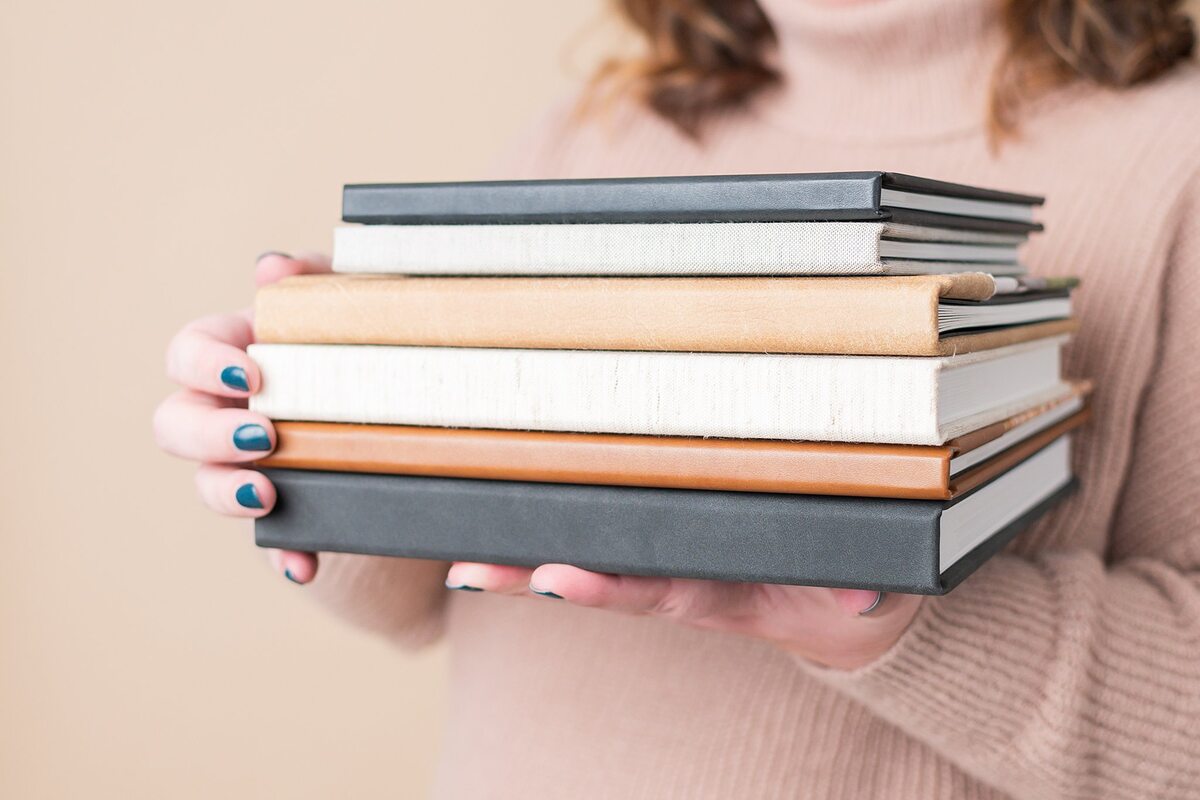 hands holding stack of books