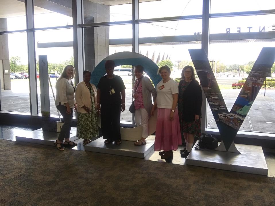 Six women standing in front of large letters LOV