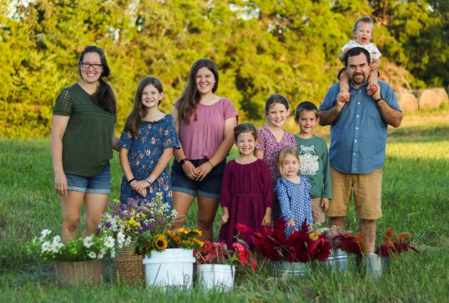 Family standing in field with buckets of flowers