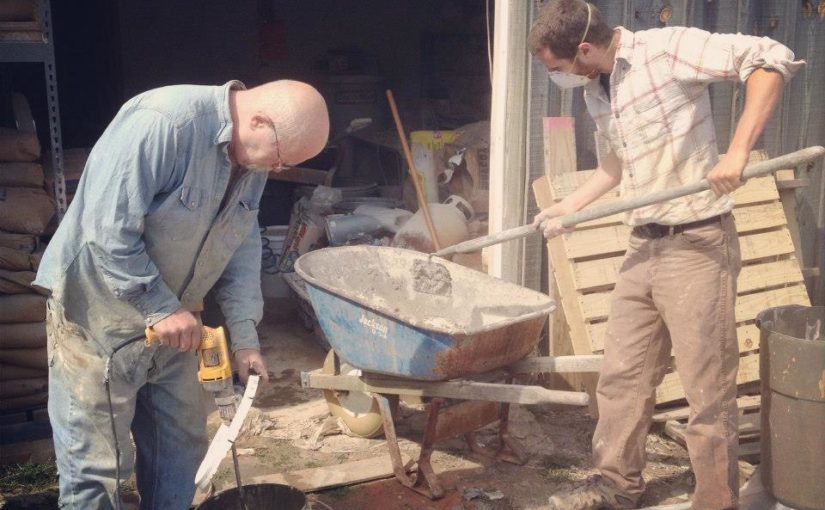 Two men with tools and wheelbarrow